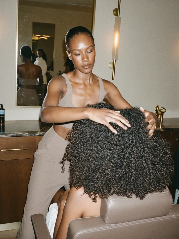 A stylist working with a client's natural curls